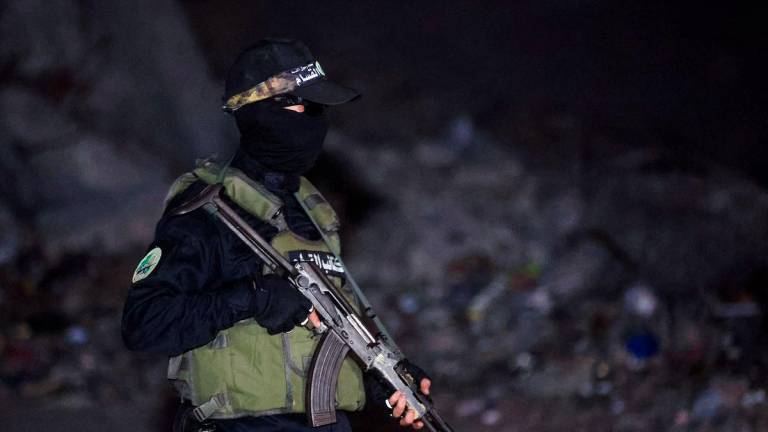 A Hamas militant stands guard as Red Cross vehicles (not pictured) transport the bodies of hostages who were held in Gaza since the deadly October 7, 2023, attack, after they were handed over by Hamas militants as part of a ceasefire and a hostage-prisoner swap deal between Hamas and Israel, in Gaza City, October 15, 2025. - REUTERSPIX