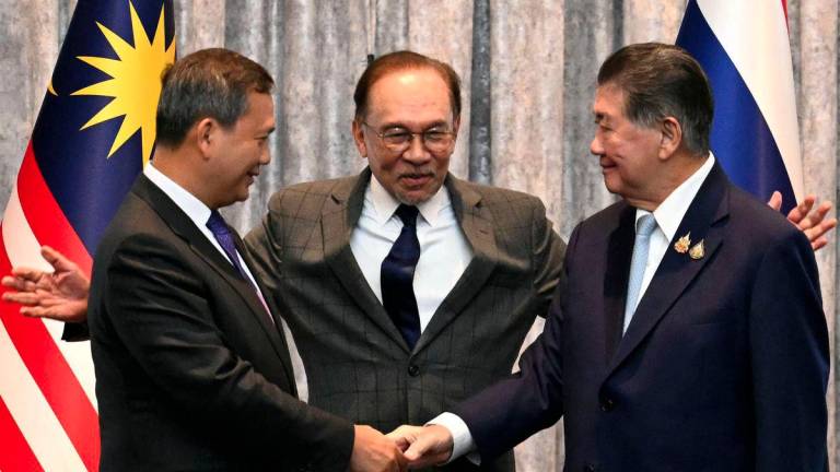 Cambodia's Prime Minister Hun Manet (L) and Thailand's acting Prime Minister Phumtham Wechayachai (R) shake hands as Malaysia's Prime Minister Anwar Ibrahim (C) puts his arms around them following a press conference after talks on a possible ceasefire between Thailand and Cambodia in Putrajaya on July 28, 2025. - AFPPIX
