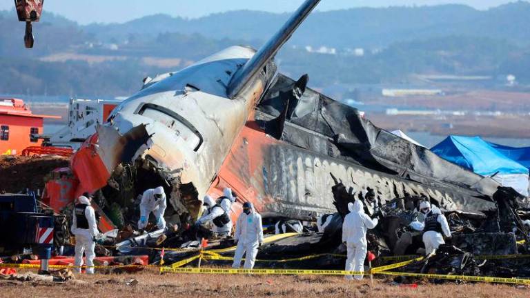 Police forensics personnel and National Bureau of Investigation officials work at the scene where a Jeju Air Boeing 737-800 aircraft crashed and burst into flames - AFPpix