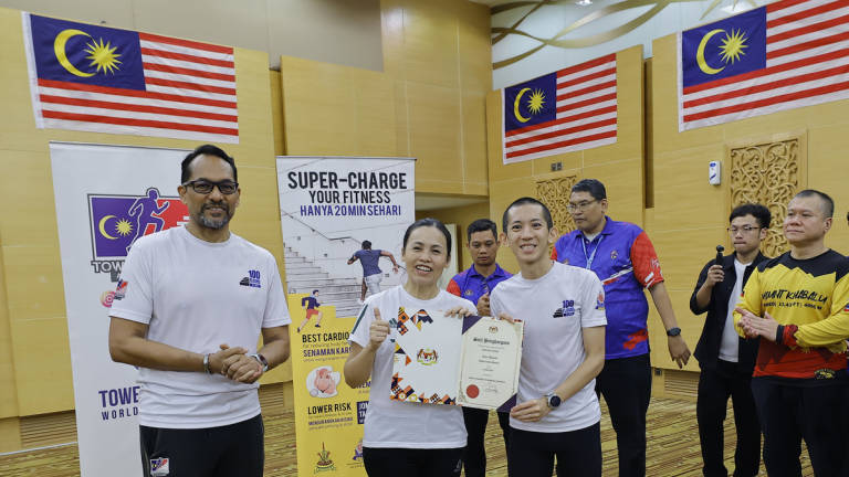 Deputy Minister of Communications Teo Nie Ching presents a certificate of appreciation to national tower running champion Soh Wai Ching after he climbed to the 37th floor of the Communications Tower during the Stair Climbing Clinic programme today. – BERNAMA