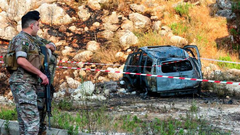 Army officers stand guard near a cordoned-off carcass of a car that was targeted in a reported Israeli drone attack in the southern Lebanese town of Al-Numairiyah on June 9, 2025. (Photo by MAHMOUD ZAYYAT / AFP)