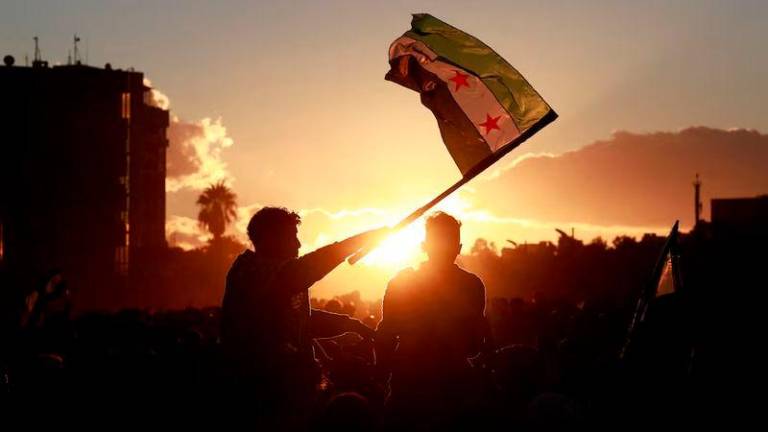 A person holds up the flag adopted by the new Syrian rulers in the Damascus old city - REUTERSpix