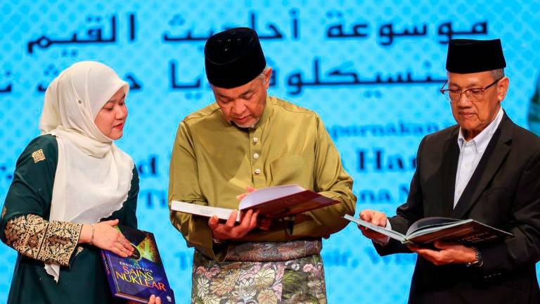 Deputy Prime Minister Datuk Seri Dr Ahmad Zahid Hamidi (centre) examines the encyclopaedia during the Launch Ceremony of the Encyclopaedia published by Dewan Bahasa dan Pustaka (DBP) and the Appointment Letter Handover Ceremony for the Translators and Verifiers of Mawsu’ah Ahadith Al-Qiyam (Encyclopaedia of Hadith on Values) Volumes One to Six, at DBP today. Also present were Education Minister Fadhlina Sidek (left) and Chairman of the DBP Board of Governors, Datuk Dr Anwar Ridhwan (right). – BERNAMA