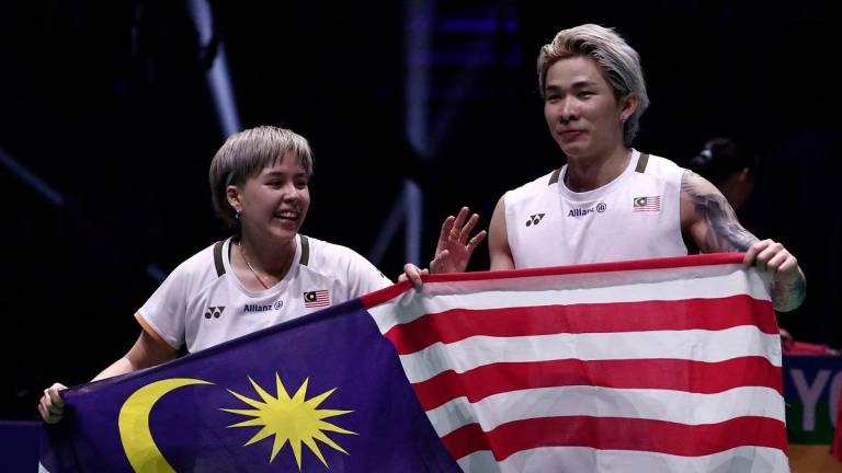 Malaysia’s Toh Ee Wei (L) and Chen Tang Jie hold their national flag as they celebrate beating China’s Jiang Zhen Bang and Wei Ya Xin in the mixed doubles final match at the Badminton BWF World Championships at the Adidas Arena in Paris, on August 31, 2025. - Thibaud MORITZ / AFP