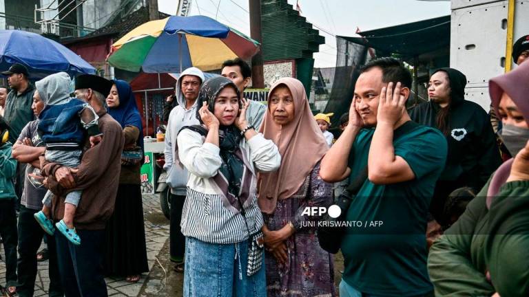 This photo taken on August 9, 2025 shows people covering their ears as a truck mounted with a tower of subwoofers drives past during a sound horeg, which loosely means to move or vibrate in Javanese, held as part of Indonesia's 80th Independence Day celebrations in Malang, East Java. - AFP