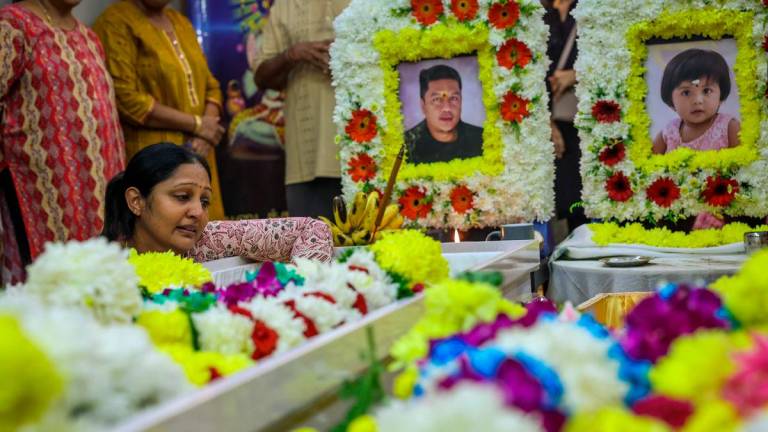 S. Sanggetha, 39, (left) pays her last respects to her late husband S. Arumugam, 40, and their daughter A. Sarrvihka, 3, at their home near Taman Bayu Aman today. Photo by BERNAMA