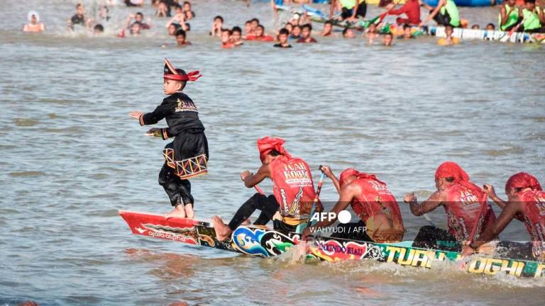 Rayyan Arkan Dikha (L), an 11-year-old boy who went viral for his calm dance on the bow of a traditional longboat, performs during the Pacu Jalur longboat race festival on the Kuantan River in Kuantan Singingi Regency, Riau Province, on August 22, 2025. - AFP