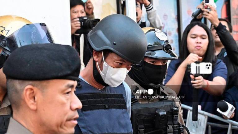 (FILES) Thai national Ekkalak Paenoi (C), a suspect in the alleged killing of former lawmaker of the dissolved Cambodia National Rescue Party (CNRP) Lim Kimya, is escorted into a police van to transport him to the Criminal Court from Chana Songkram Police Station in Bangkok on January 13, 2025. A Thai gunman was sentenced to life in prison on October 3, 2025 for the murder of Cambodian opposition politician Lim Kimya in Bangkok, the judge said. - AFP