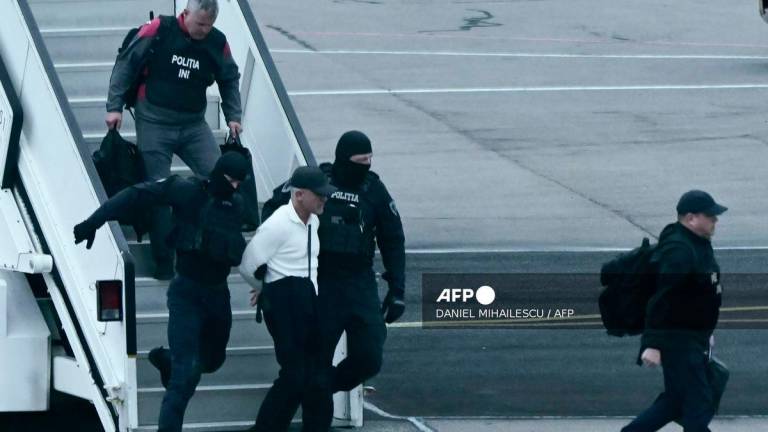 Masked police officers escort Moldovan oligarch Vladimir Plahotniuc (C), accused of acting of behalf of Russia, as they disembark an aircraft after his extradition from Greece following his arrest earlier in July, at Chisinau International Airport, on September 25, 2025. (Photo by Daniel MIHAILESCU / AFP)
