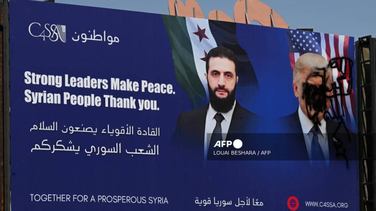 A picture shows a promotional poster bearing the portrait of Syria’s interim President Ahmad al-Sharaa and a defaced portrait of US President Donald Trump in the capital Damascus on July 9, 2025. - AFP