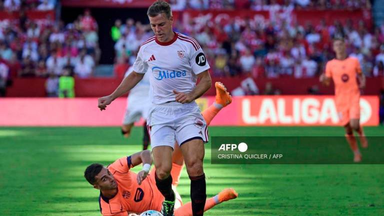 Sevilla's Spanish defender #03 Cesar Azpilicueta and Barcelona's Spanish forward #07 Ferran Torres (BOTTOM) fight for the ball during the Spanish league football match between Sevilla FC and FC Barcelona at Ramon Sanchez Pizjuan Stadium in Seville on October 5, 2025. - AFP