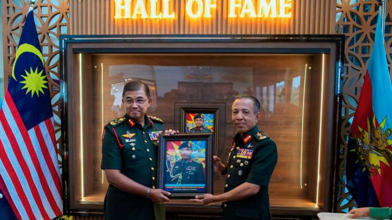 Malaysian Armed Forces (MAF) Chief General Tan Sri Mohd Nizam Jaffar (left) receives a souvenir from National Resilience College Commandant Brigadier General Abdul Karim Ahmad as they pose for a photo at the inaugural National Resilience College (MKN) Hall of Fame Proclamation Ceremony at MKN today. – BERNAMA