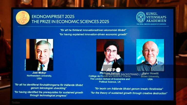 A screen displays the portraits of the 2025 prize winners (L-R) Joel Mokyr, Philippe Aghion and Peter Howitt, during the announcement of the winners of the 2025 Nobel Prize in Economics, the Sveriges Riksbank Prize in Economic Sciences in Memory of Alfred Nobel, at the Royal Swedish Academy of Sciences in Stockholm, Sweden, on October 13, 2025. - AFP