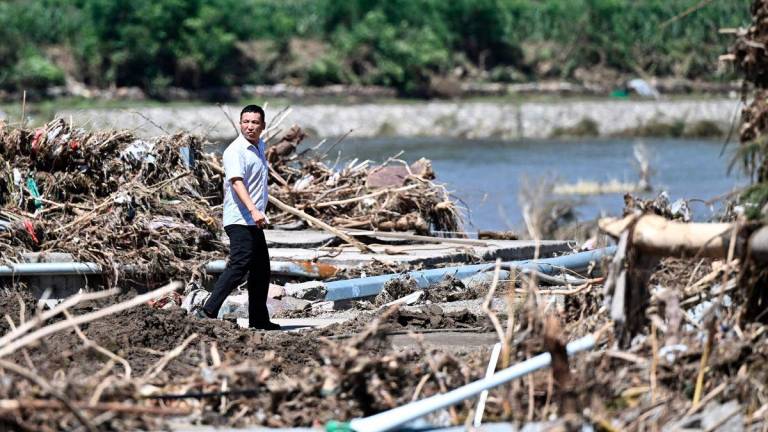 A man walks past a rain damaged area from the past few days in Huairou district, on the outskirts of Beijing on July 30, 2025. (Photo by Pedro Pardo / AFP)