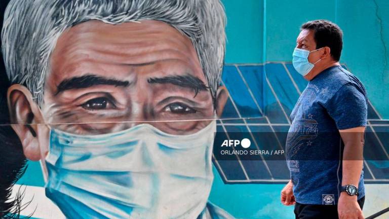 A man wears a surgical mask as he walks down an avenue in Tegucigalpa on July 24, 2025. - AFP
