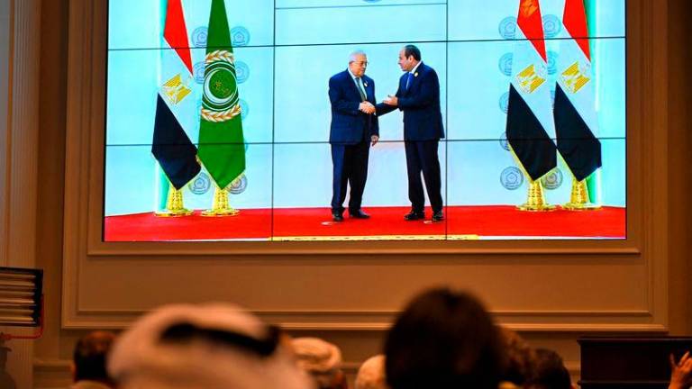 People watch on a big screen as Egypt’s President Abdel Fattah al-Sisi (R) welcomes Palestinian President Mahmud Abbas ahead of an Arab League summit on Gaza on March 4, 2025. AFP pix