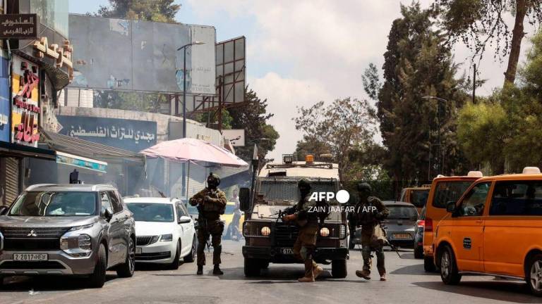 Israeli soldiers block a road during a raid in the city of Ramallah, in the Israeli occupied West Bank, on August 26, 2025. (Photo by Zain JAAFAR / AFP)
