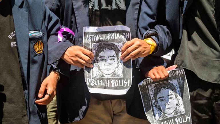 Demonstrators hold portraits of Affan Kurniawan, a motorcycle taxi driver who was run over by a police Mobile Brigade Corps or ‘Brimob’ armoured vehicle on August 28, during a protest in front of the Regional Police headquarters in Surabaya on August 30, 2025. (Photo by JUNI KRISWANTO / AFP)