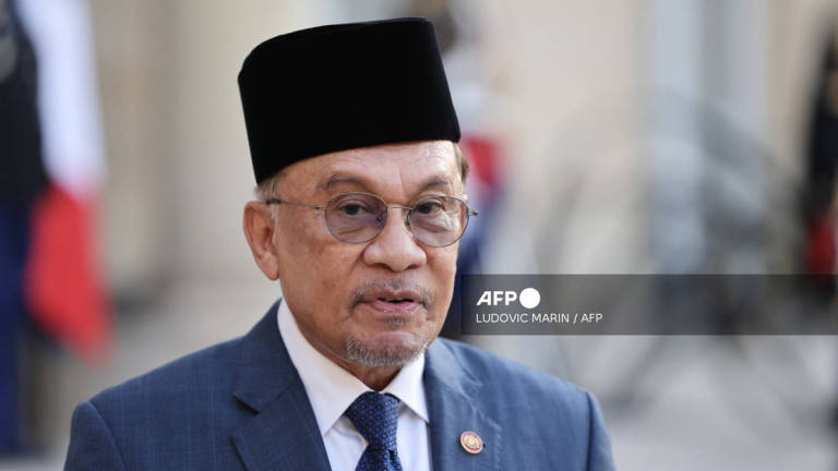 Malaysia's Prime Minister Anwar Ibrahim speaks next to France's President Emmanuel Macron during a joint press statement prior to a working dinner at the Elysee Palace in Paris on July 4, 2025. - AFP