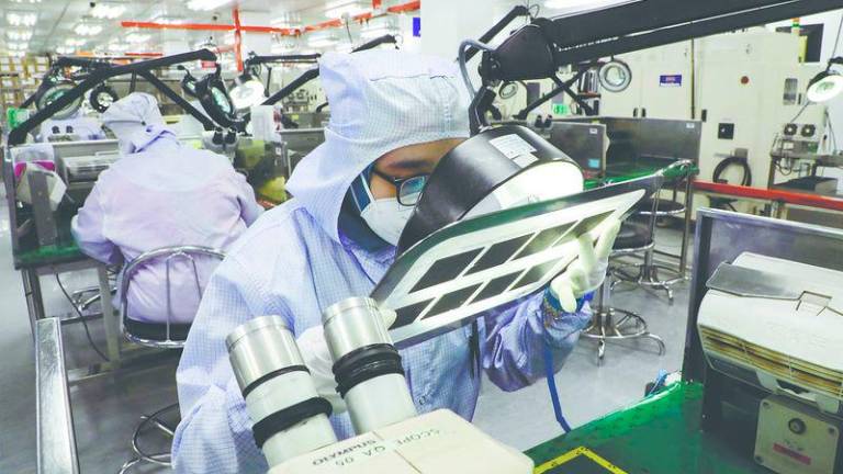 A worker inspects semiconductor chips at a chip packaging firm in Ipoh, Malaysia. – REUTERSPIC