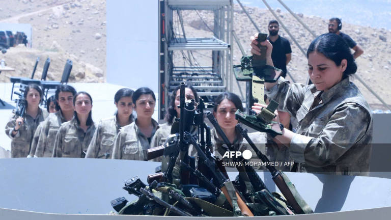 Fighters with the Kurdistan Workers’ Party (PKK) line up to put their weapons into a pit during a ceremony in Sulaimaniyah, in Iraq’s autonomous Kurdistan region, on July 11, 2025. - AFP