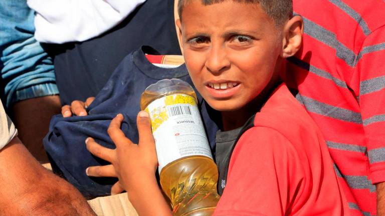 A youngster carries food aid as Palestinians seeking aid gather near an aid distribution site run by the U.S.-backed Gaza Humanitarian Foundation, in Rafah, in the southern Gaza Strip, May 27, 2025. REUTERSpix
