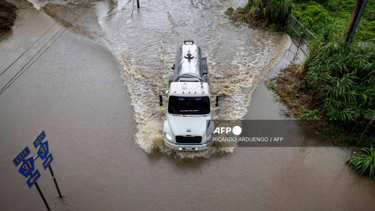 A truck drives through a flooded road as category 3 Hurricane Erin leaves the region in Naguabo, Puerto Rico on August 16, 2025. (Photo by Ricardo ARDUENGO / AFP)