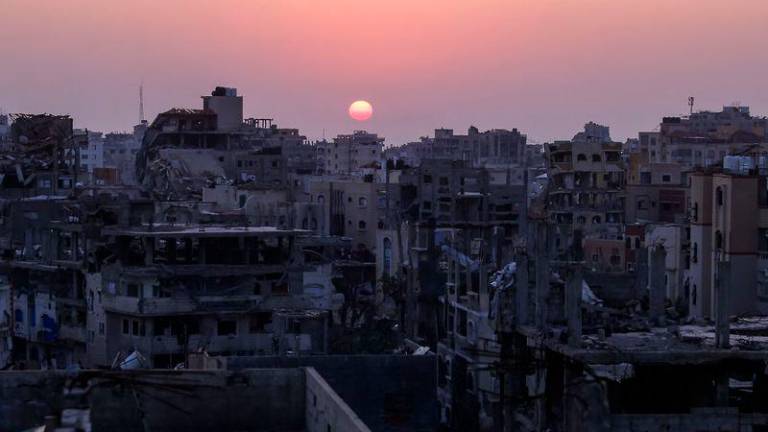 The sun sets behind heavily damaged residential buildings in Jabalia in the northern Gaza Strip - AFPpix