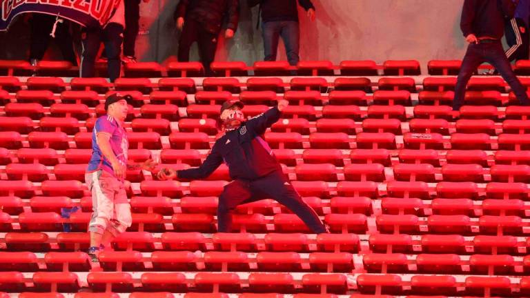 A fan of Universidad de Chile prepares to throw a stone during the interruption of the Copa Sudamericana round of 16 second leg football match between Argentina’s Independiente and Chile’s Universidad de Chile at the Libertadores de America stadium in Avellaneda, Buenos Aires province, Argentina on August 20, 2025. (Photo by Alejandro PAGNI / AFP)