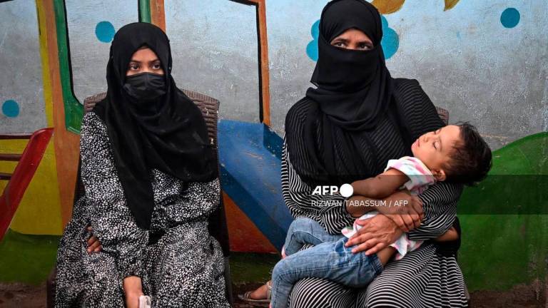 In this photograph taken on July 31, 2025, Amina (L), a household helper, sits beside her mother as she speaks during an interview with AFP in Karachi. Photo by RIZWAN TABASSUM / AFP
