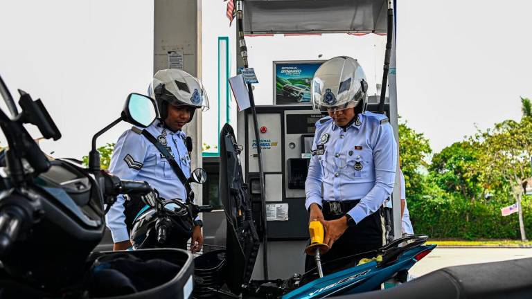 Jurugambar Trafik Ibu Pejabat Daerah (IPD) Seremban Azrin Abd Aziz (kanan) mengisi petrol RON95 di stesen Petronas S2 City Park pada harga RM1.99 seliter, berbanding harga pasaran RM2.05 seliter, menerusi inisiatif BUDI MADANI RON95 (BUDI95) yang bermula hari ini- BERNAMA