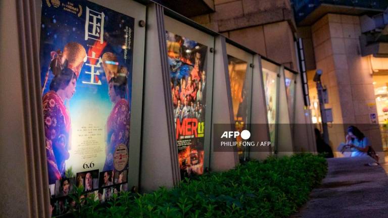 The poster of Japanese movie Kokuho (L) is pictured outside a cinema in Tokyo's Roppongi district on September 4, 2025. - AFP