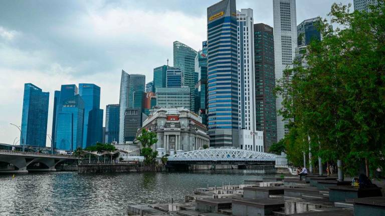 People sit along the promenade under a cloudy sky during lunchtime in the financial district of Raffles Place in Singapore on May 22, 2025. AFPpix
