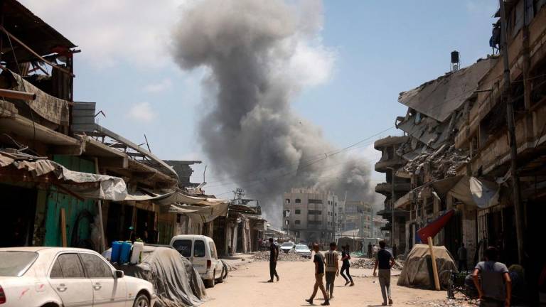 Palestinian watch as a plume of smoke rises during an Israeli strike on Gaza City’s southern al-Zeitoun neighbourhood on August 8, 2025. Israel’s military will “take control” of Gaza City under a new plan approved by Prime Minister Benjamin Netanyahu’s security cabinet, touching off a wave of criticism Friday from both inside and outside the country. - BASHAR TALEB / AFP