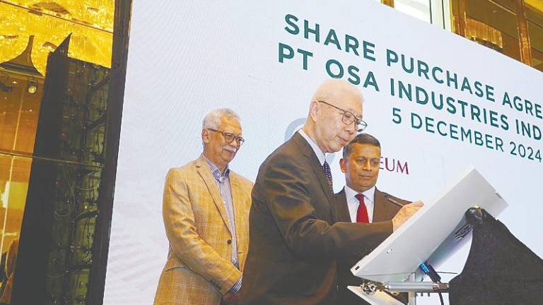 OSA Industries Pte Ltd founder and director Ong Siow Aik signing the agreement while Deleum non-executive chairman Tan Sri Shamsul Azhar Abbas (left) and Rao look on.