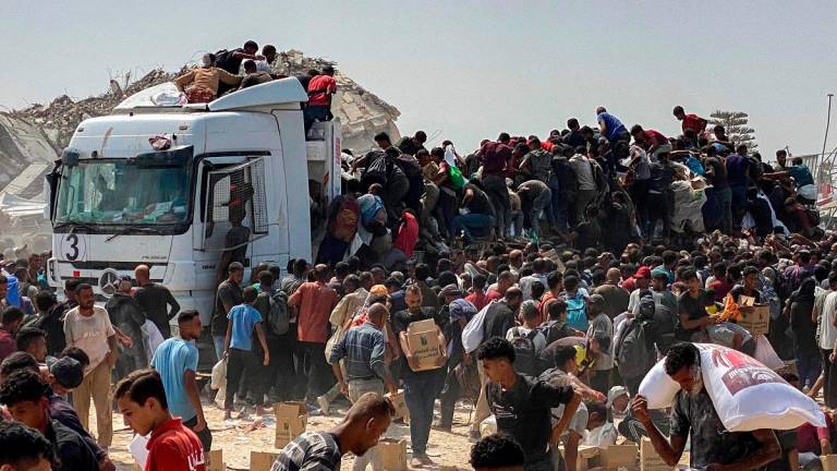 Displaced Palestinians carry food parcels as they raid trucks carrying humanitarian aid in Khan Yunis, in the southern Gaza Strip on August 9, 2025. - AFPpix