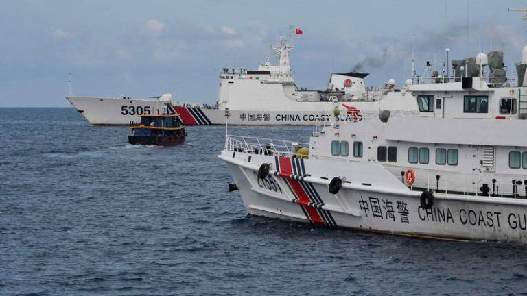Chinese coast guard ships (L and R) corralling a Philippine civilian boat chartered by the Philippine navy to deliver supplies to Philippine navy ship BRP Sierra Madre in the disputed South China Sea - AFPpix