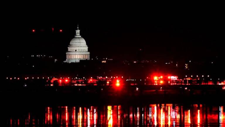 Emergency personnel work near the site of the crash, with the U.S. Capitol in the background, after American Eagle flight 5342 collided with a Black Hawk helicopter while approaching Ronald Reagan Washington National Airport and crashed in the Potomac River - REUTERSpix