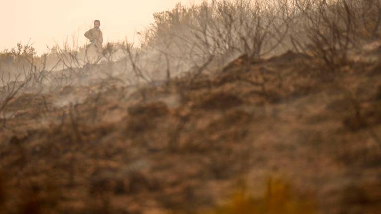 A resident stands in a burned field as he battles a wildfire in the locality of Colinas del Campo de Martin Moro Toledano, province of Leon, northwestern Spain on August 21, 2025. - Cesar Manso / AFP