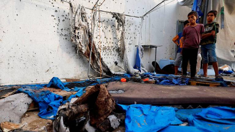 Kanak-kanak Palestin berdiri di lokasi serangan Israel ke atas sebuah khemah berhampiran Hospital Shifa yang mengorbankan wartawan Al Jazeera Anas Al Sharif, Mohammed Qreiqeh, Ibrahim Zaher, dan Mohammed Noufal, di Bandar Gaza pada 11 Ogos 2025. REUTERS/Mahmoud Issa