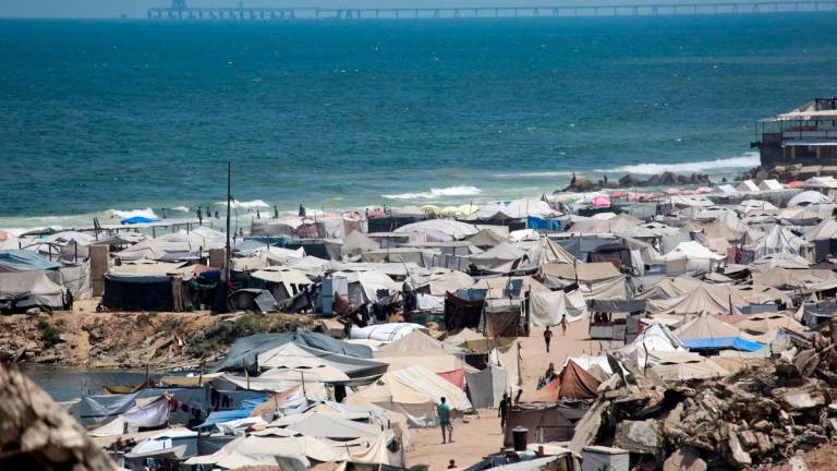 Tents used as temporary shelters by displaced Palestinians are set up around war-damaged structures along the beach in Gaza City on August 8, 2025. AFP