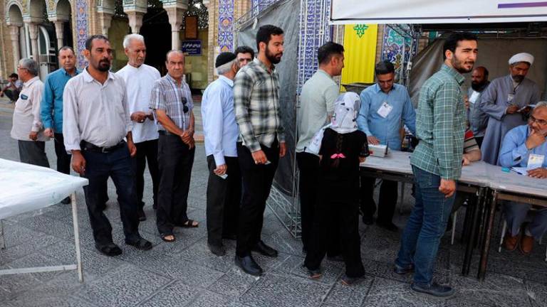 Iranian people stand in a queue as they wait to vote at a polling station in a snap presidential election to choose a successor to Ebrahim Raisi following his death in a helicopter crash, in Tehran, Iran June 28, 2024. Majid Asgaripour/WANA (West Asia News Agency) via REUTERS