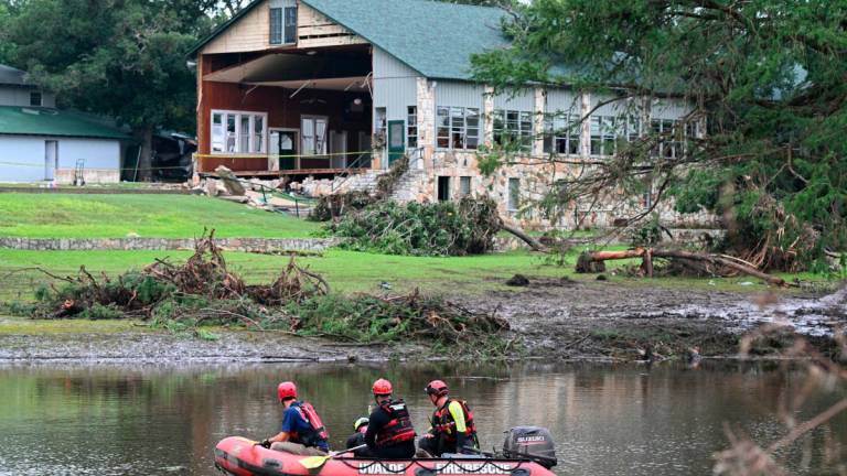 A search and rescue team looks for people along the Guadalupe River near a damaged building at Camp Mystic in Hunt, Texas, on July 7, 2025, following severe flash flooding that occurred during the July 4 holiday weekend. - RONALDO SCHEMIDT / AFP