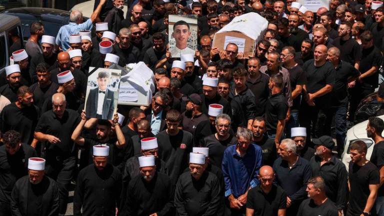 Mourners carry the coffins and pictures of people killed in a rocket strike from Lebanon a day earlier, during a mass funeral in the Druze town of Majdal Shams in the Israel-annexed Golan Heights - AFPpix