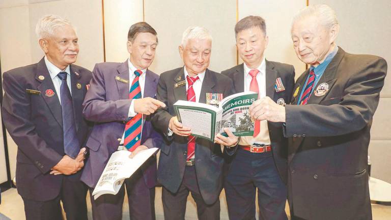 From second left: Wong, Lee and Liew browsing through Memoirs 1 and 2. – ADIB RAWI YAHYA /THESUN