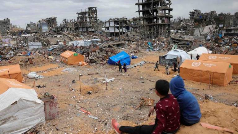 Displaced Palestinian children sit on a sand mound overlooking tents set up amid destroyed buildings in Jabalia in the northern Gaza Strip - AFPpix