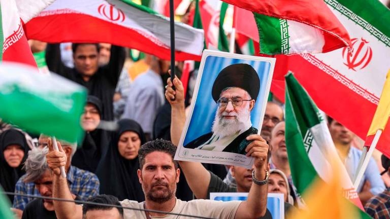 An Iranian man holds a portrait of supreme leader Ayatollah Ali Khamenei as people celebrate a ceasefire between Iran and Israel at Enghlab Square in the capital Tehran on June 24, 2025. - ATTA KENARE / AFP