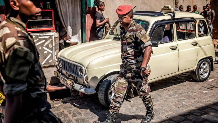 Members of Madagascar’s Army CAPSAT unit walk past an old taxi near the CAPSAT base, a day after the unit announced it would assume power in Antananarivo, on October 15, 2025. - Luis TATO / AFP