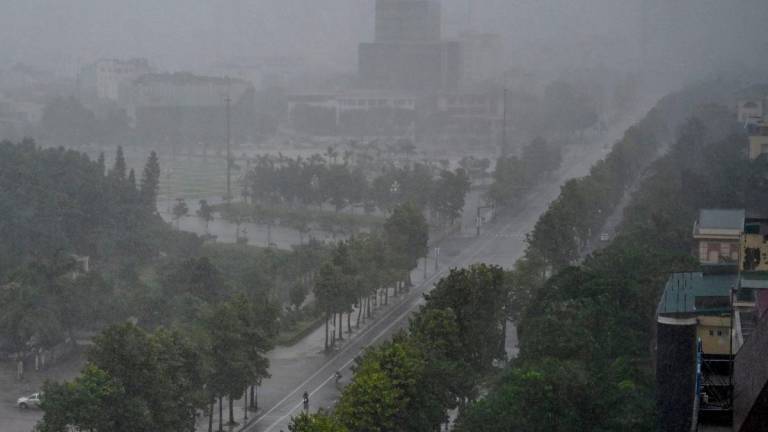 Rain falls above the buildings and a street in Vinh city, Nghe An province on August 25, 2025, before Typhoon Kajiki makes landfall in Vietnam. Tens of thousands of residents were being evacuated from coastal Vietnam on August 25, as Typhoon Kajiki barrelled towards landfall expected to lash the country’s central belt with gales of around 160 kmh. The typhoon -- the fifth to affect Vietnam this year -- is currently at sea, roiling the Gulf of Tonkin with waves of up to 9.5 metres (31 feet). (Photo by Nhac NGUYEN / AFP)