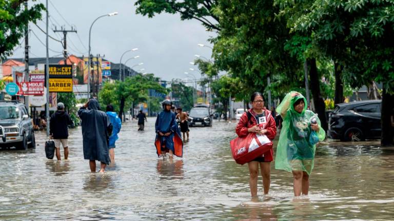 FILE PHOTO: People carrying their belongings wade through a flooded street following overnight heavy rains in Legian, Badung, Bali, Indonesia September 10, 2025. REUTERS/Dicky Bisinglasi/File Photo
